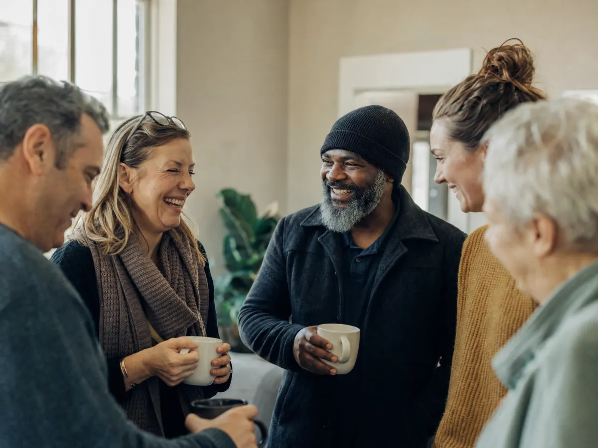 Adults of different ages sharing coffee and laughing together in a community room